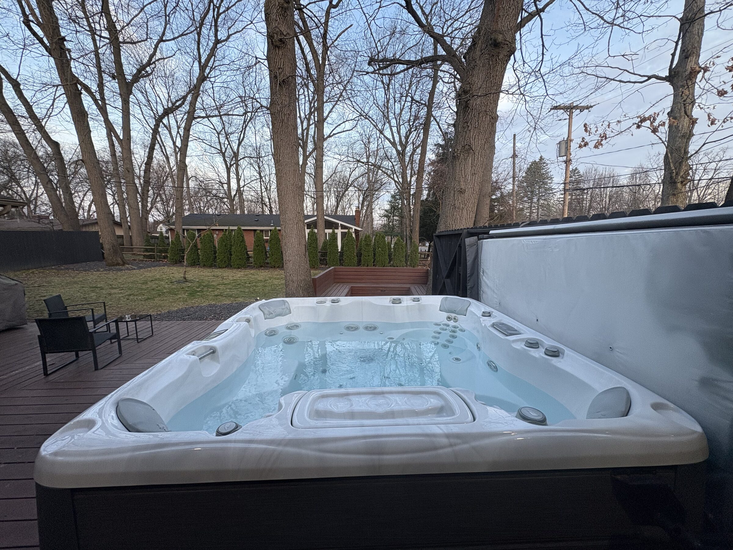 Backyard with private hot tub and stone fire pit at dusk