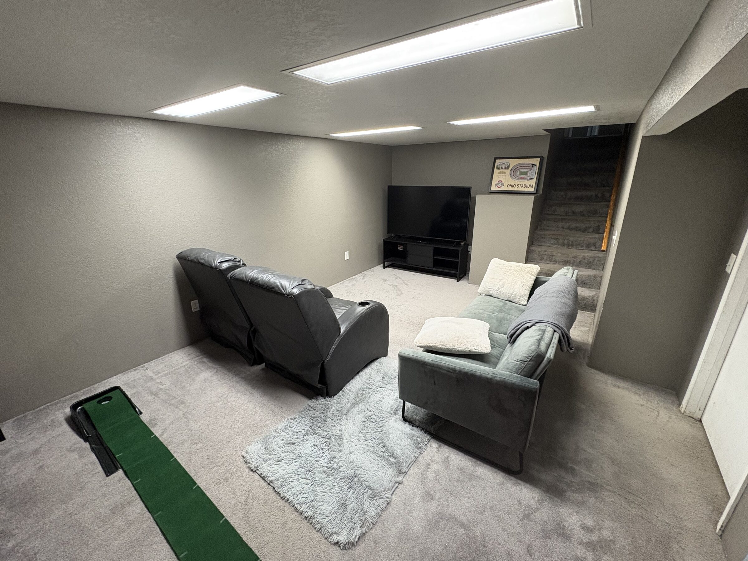 Lower-level lounge with recliners, second TV and putting green